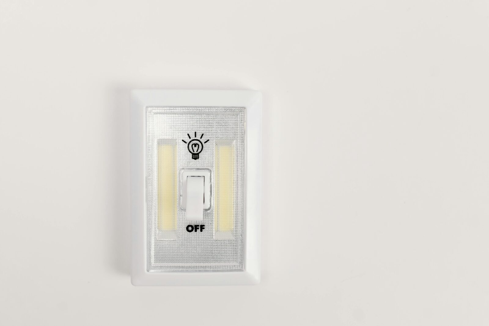 Minimalist light switch turned off on a plain white wall,