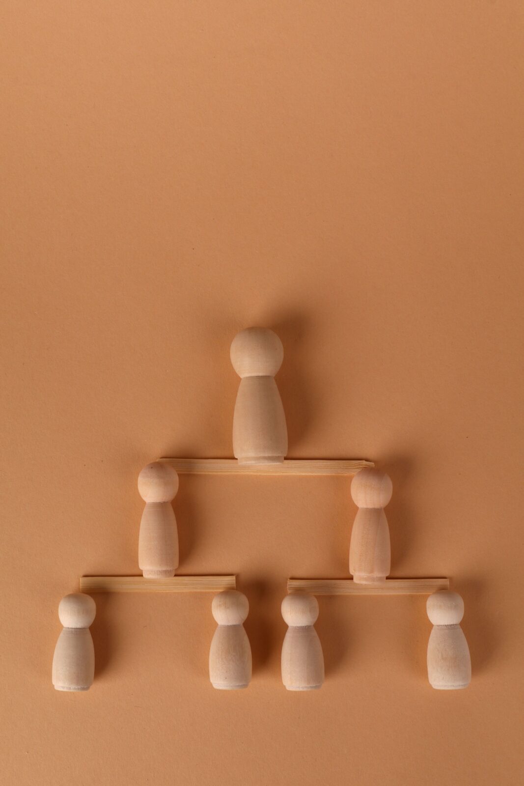 Minimalist representation of a hierarchy using wooden peg dolls on a brown background